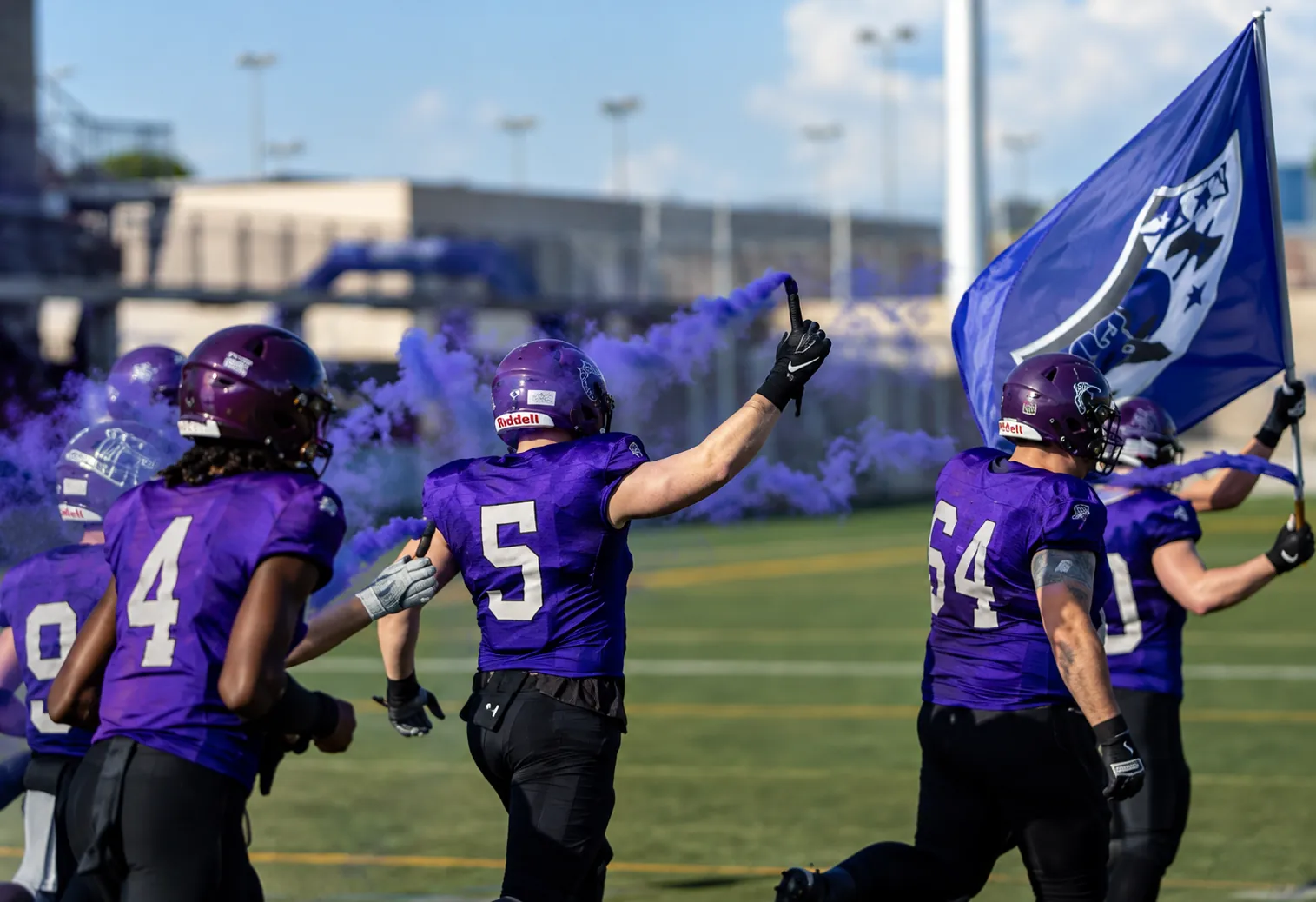Gladiators Basel players running onto the field with flag and purple smoke